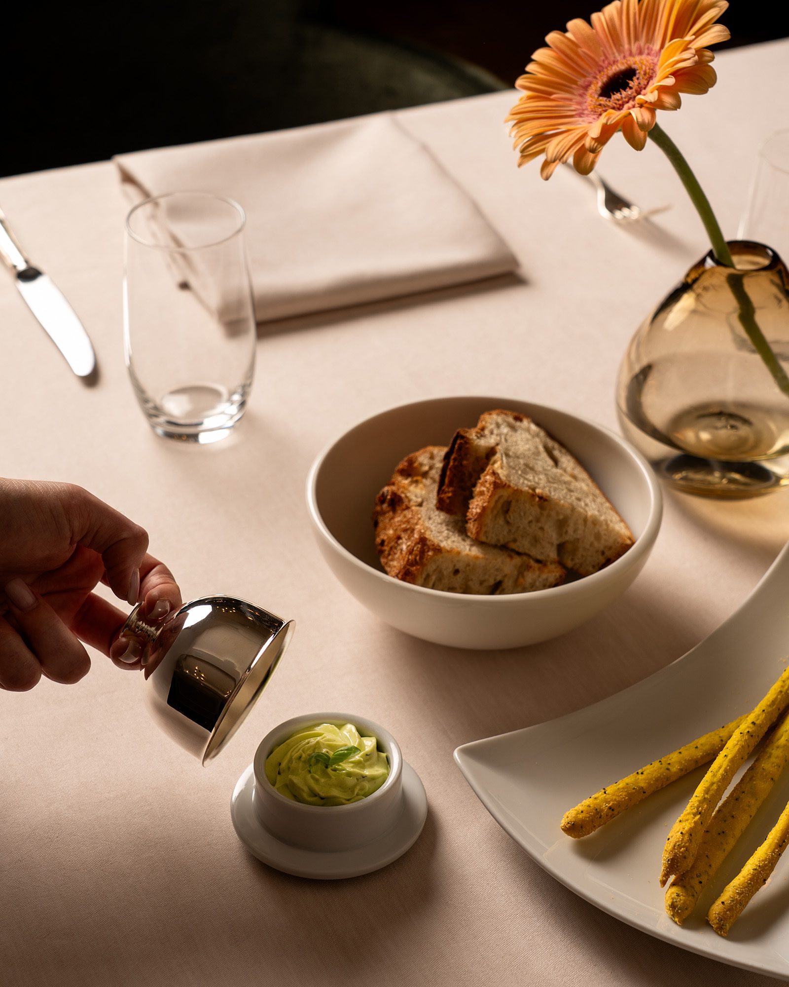 Elegant gedeckter Tisch mit Brot, Grissini und Kräuterbutter