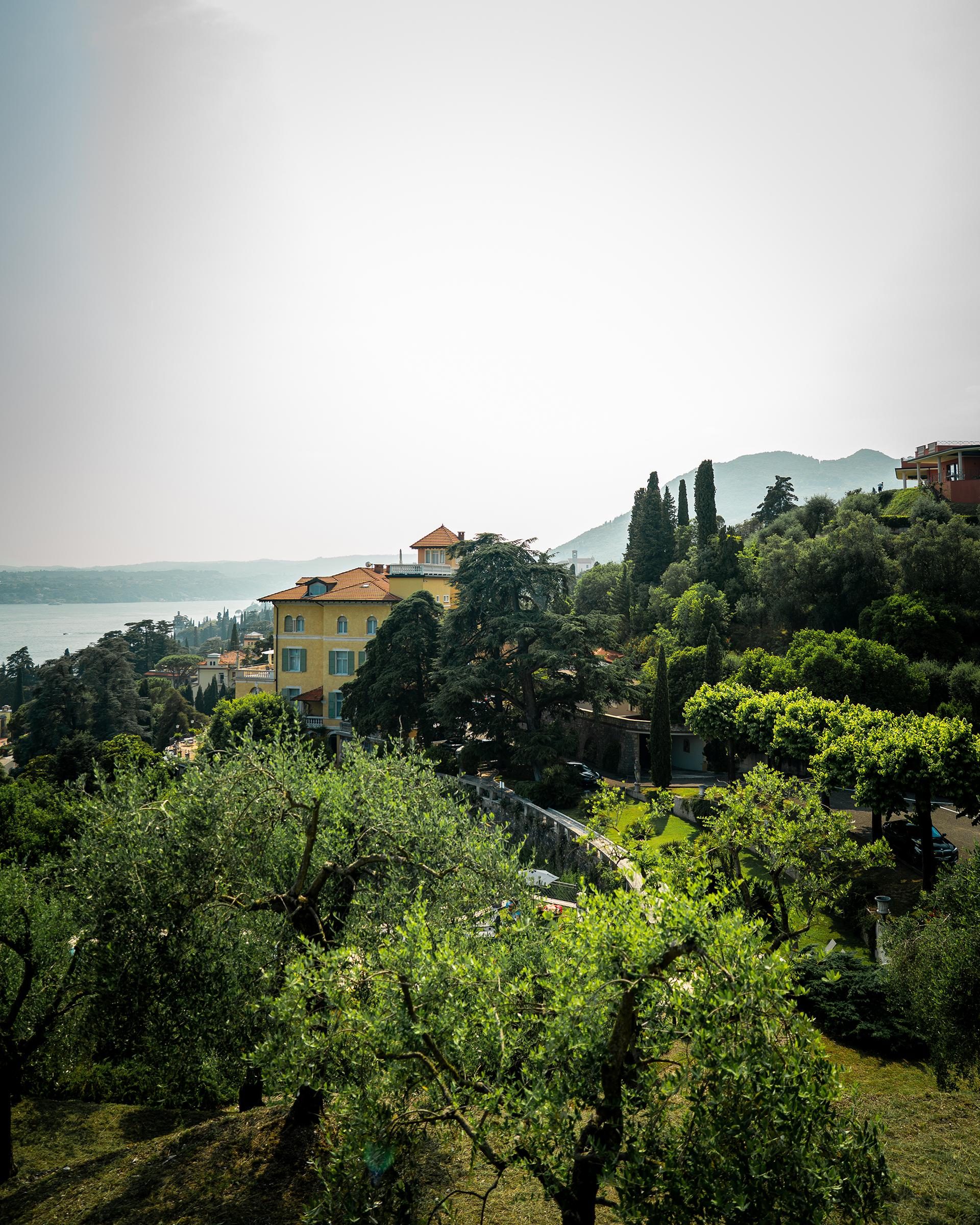 Gelbe Villa zwischen Olivenbäumen und Zypressen mit Seeblick und Hügeln