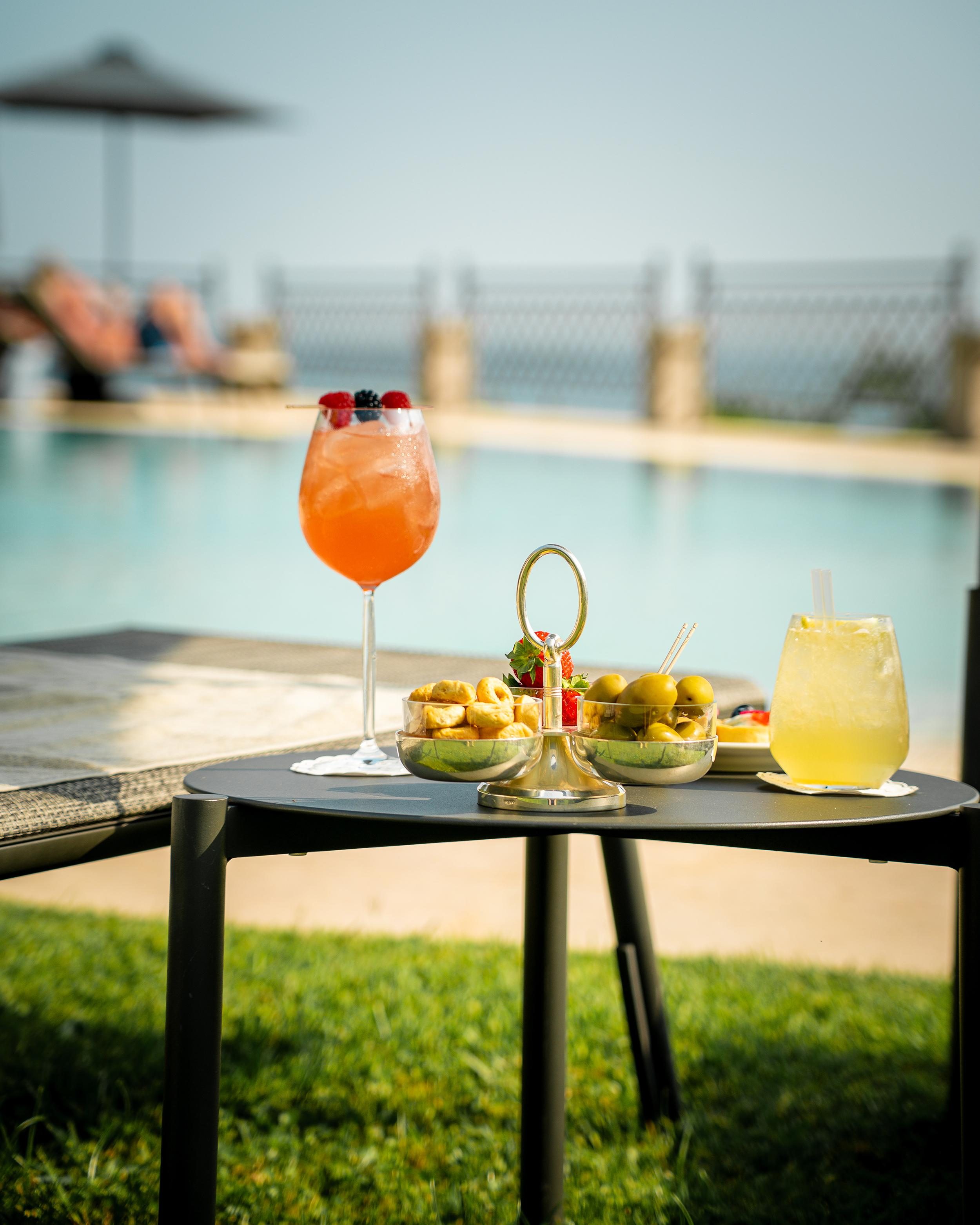 Zwei Getränke mit Oliven-Snacks am Pool