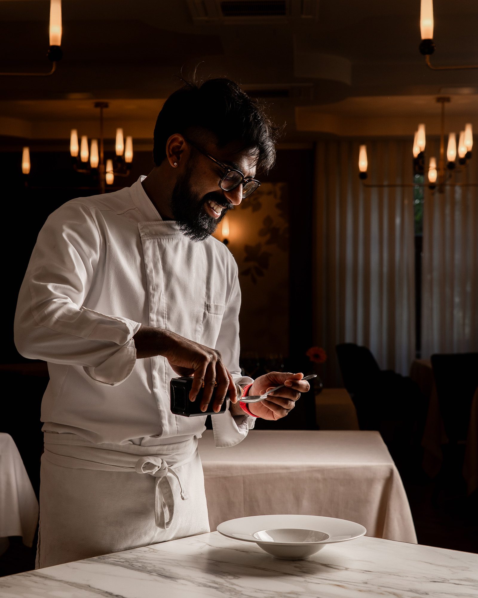 Koch gießt Sauce auf Löffel im edlen Restaurant