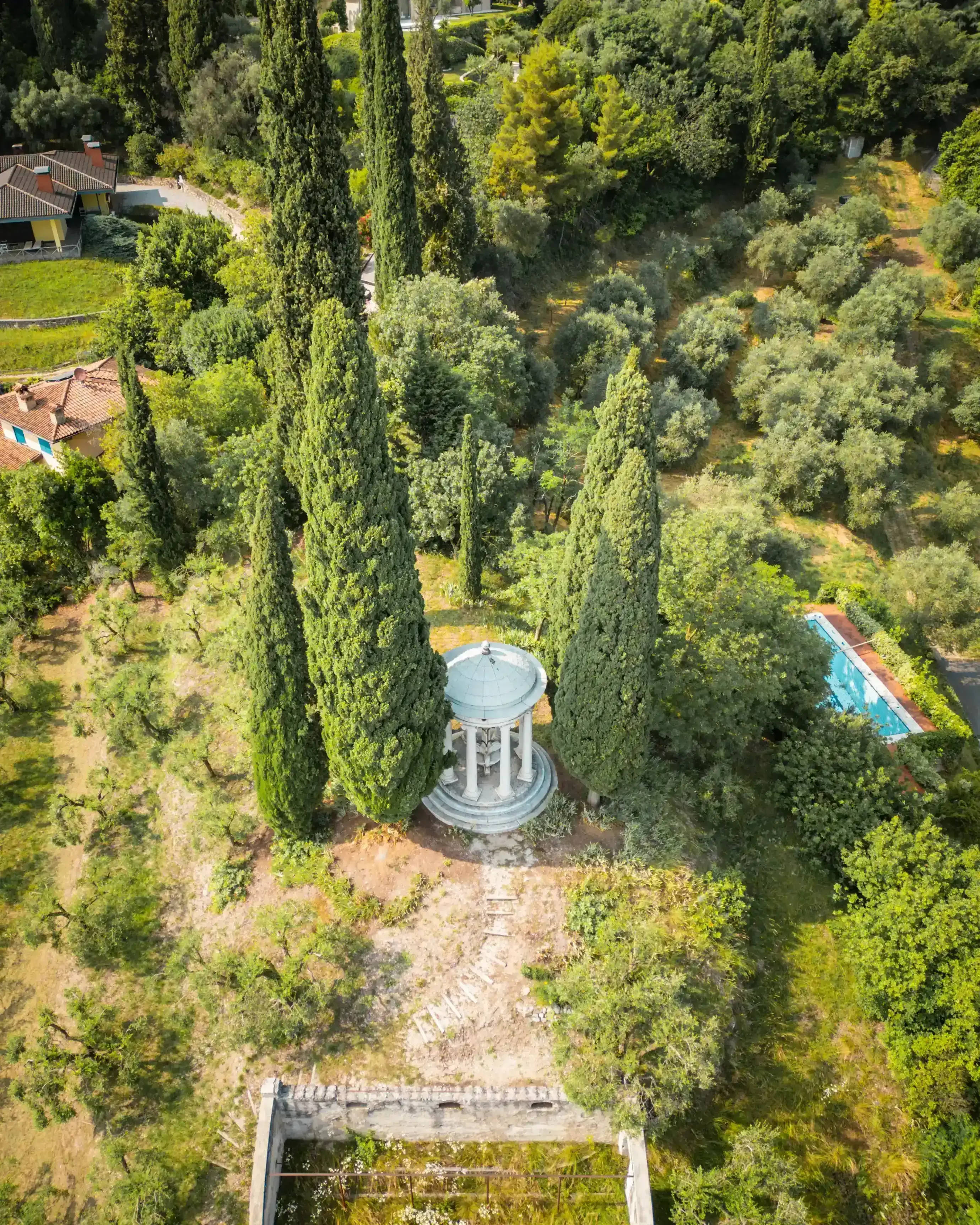 Vista aerea di un tempietto neoclassico tra alti cipressi in giardino mediterraneo